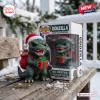 Front view of Godzilla 2026 Christmas Vinyl Figure wearing a Santa hat and holding a red gift box next to its packaging.