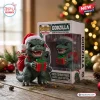 Front view of Godzilla 2026 Christmas Vinyl Figure wearing a Santa hat and holding a red gift box beside its packaging.