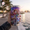 Hand holding a Vice City tumbler cup featuring character artwork against a sunset waterfront.