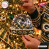 Closeup of Green Bay Packers Ice Bowl Christmas Ornament held near a lit tree.