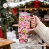 Hand holding a pink 40oz tumbler with Merry Grinchmas holiday graphics and handle.