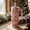 Front view of a pink Grinch Christmas 40oz tumbler with holiday illustrations on a wooden table.
