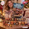 A smiling woman holding the Grumpy Highland Cows 2026 Advent Calendar with figurine toys displayed on a table.