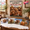 Front view of Grumpy Highland Cows 2027 Wall Calendar displayed on wooden table with seasonal month pages.
