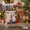 Hand holding a Hallmark Wonder Woman 50th Anniversary Ornament next to its packaging box on a wooden table.