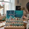 Person unboxing a Hatsune Miku Magical Advent Calendar with collectible mini figurines on display tiers.