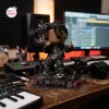 Front view of the Ken Carson Chaos Vinyl Figurine on a studio desk with a computer monitor and audio equipment.
