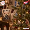 Front view of Knights Medieval Advent Calendar box next to a decorated Christmas tree with knight ornaments.
