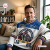 Man wearing Knights of Columbus white hoodie with blue and red accents while seated on a sofa.