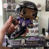 Close-up of Lamar Jackson Baltimore Ravens vinyl figurine held in a hand over a stadium base.