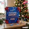 Front view of blue Los Angeles Dodgers 2026 Advent Calendar box with red bows and figurines on a wooden table.
