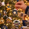 Close-up of a hand hanging baseball-themed ornaments on a Christmas tree for the Milwaukee Brewers fans.