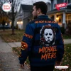 Rear view of a man wearing a blue varsity jacket featuring a mask graphic and text.