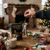 Hand holding a Miles Davis 100th Anniversary Resin Ornament near a holiday tree.