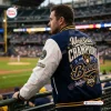 Rear view of a man wearing a Milwaukee Brewers 2026 World Series Champions Baseball Jacket at a stadium.