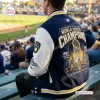 Back view of a fan wearing the Milwaukee Brewers 2026 World Series Champions Baseball Jacket at a ballpark.