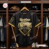 Front view of a black baseball jersey with gold World Series Champions graphics hanging in a wooden locker room.