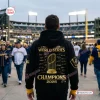 Back view of a person wearing a Milwaukee Brewers 2026 World Series Champions black hoodie at a stadium.