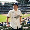 Man wearing Milwaukee Brewers 2026 World Series Champions cream baseball jersey at stadium.
