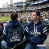 Two men wearing blue Milwaukee Brewers 2026 World Series Champions hoodies at a stadium.