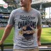 Front view of a fan wearing a grey Milwaukee Brewers 2026 World Series Champions shirt at a stadium.