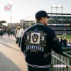 Back view of a person wearing the Milwaukee Brewers 2026 World Series Champions varsity jacket at a baseball stadium.