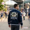 Back view of a man wearing the Milwaukee Brewers 2026 World Series Champions varsity jacket outside a stadium.