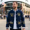 Front view of a man wearing a blue Milwaukee Brewers Champions Varsity Jacket outside a stadium.