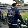 Rear view of a man wearing a blue Milwaukee Brewers Champions Varsity Jacket inside a stadium.