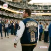 Back view of a person wearing a Milwaukee Brewers World Series Champions varsity jacket at a stadium.