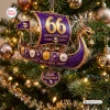 Closeup of a purple and gold Viking ship Christmas ornament hanging on a pine tree.