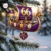 Close-up of a purple and gold Viking ship Christmas ornament hanging on a snowy pine tree branch.