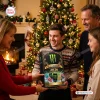 Family gathered by a decorated Christmas tree holding the Monster Energy All Flavors Advent Calendar 2026.
