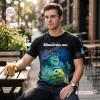 Front view of man wearing Monsters Inc 25th Anniversary Black Shirt while holding iced coffee.
