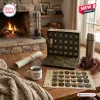 Front view of a National Park Adventure Advent Calendar on a wooden table with a map and mug near a fireplace.