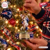 Hands hanging a football player figure on a Christmas tree as part of the New England Patriots Efton Chism III Christmas Ornament.