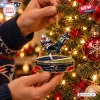Close-up of a Christmas ornament depicting a football goal-line interception hanging on a lit tree.