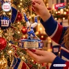 Close-up of hands hanging a New York Giants Cam Skattebo Christmas Ornament on a tree.