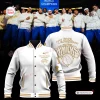 Front and back views of a white and gold New York Knicks 2026 Champions Baseball Jacket against a team celebration background.