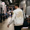 Rear view of a man walking in a stadium hallway wearing the New York Knicks 2026 Champions Baseball Jacket.