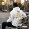 Rear view of a person wearing a white New York Knicks 2026 NBA Champions hoodie while seated on a bench outdoors.