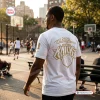 Back view of a person wearing a white New York Knicks 2026 NBA Finals Championship shirt on an outdoor basketball court.