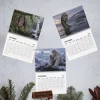 Flat lay of three open pages from the Nicolas Cage Cryptids 2027 Wall Calendar showing October, November, and December.