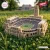 High-angle view of a Notre Dame Fighting Irish plush stadium pillow resting on green grass outdoors.