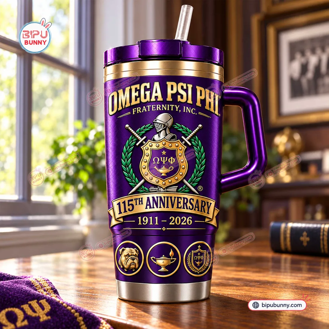 Indoor desktop view of the Omega Psi Phi 115th Anniversary Purple Handle Tumbler highlighting the heraldic shield crest and 1911-2026 banner