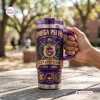 Hand holding an Omega Psi Phi 115th Anniversary Purple Handle Tumbler outdoors on a wooden table.
