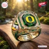 Closeup of Oregon Ducks 132nd Anniversary 1894-2026 Ring with green stone and duck mascot on wood surface.