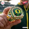 Closeup of a gold Oregon Ducks anniversary ring with green center stone and mascot side engraving.