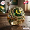 Closeup of the Oregon Ducks 132nd Anniversary 1894-2026 Ring featuring a green center stone and mascot on a wooden table.