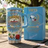 Front view of Peanuts 77th Anniversary YETI Handle Tumbler in blue with character graphics next to a matching box.